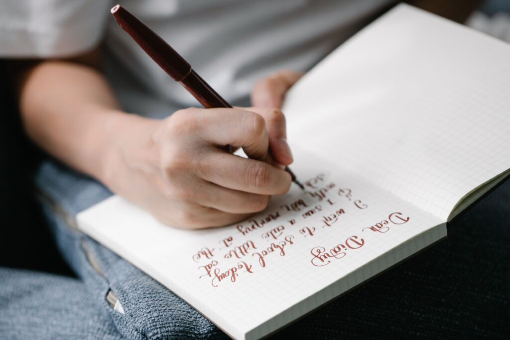 Writing down thoughts and to-do lists in a journal next to a bed